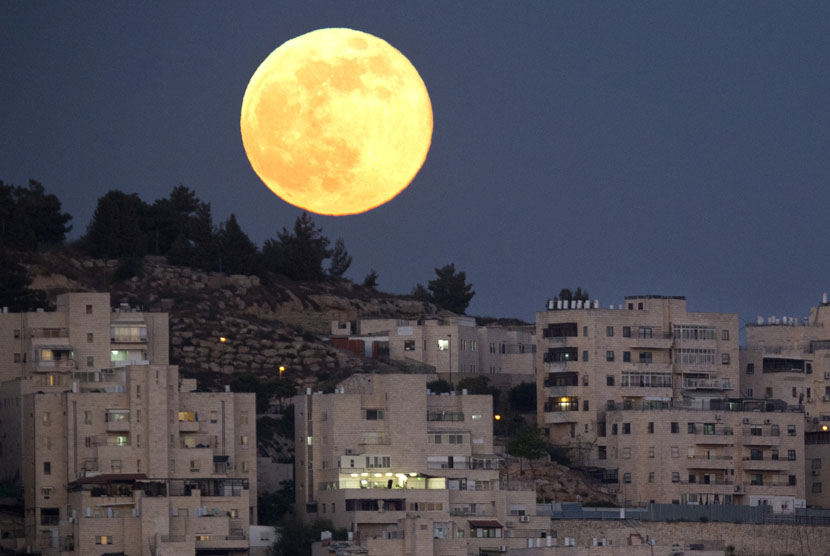 Bulan purnama tampak di langit kota suci Yerusalem, Ahad (23/6).    (AP/Jim Hollander)