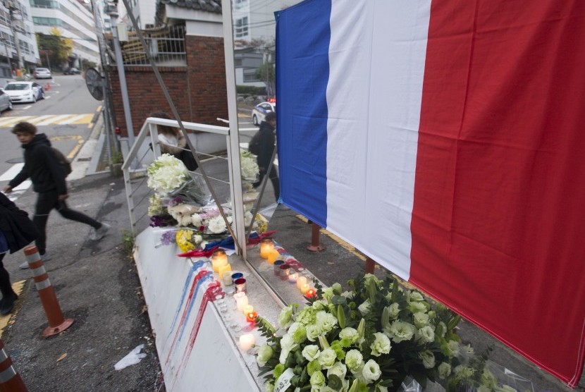 Bunga dan lilin yang menyala diletakkan di depan Kedubes Prancis di Seoul, Korsel, (16/11), sebagai bentuk simpati atas teror Prancis.