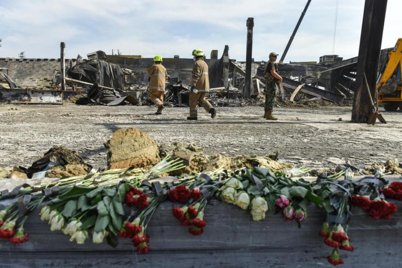 Bunga diletakkan di depan puing-puing pusat perbelanjaan Amstor di Kremenchuk, kawasan sentral Ukraina, Rabu (29/6/2022). Sebanyak 18 orang meninggal akibat serangan udara ke mal tersebut pada Senin (27/6/2022) petang. 