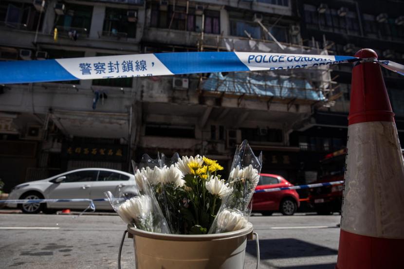 Bunga diletakkan sebagai tanda penghormatan terhadap korban meninggal di depan apartemen yang terbakar di Hong Kong pada 16 November 2020.