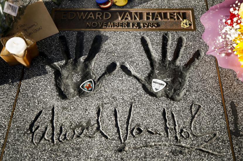 Bunga, lilin, dan pick gitar diletakkan di cap tangan Eddie Van Halen di Rock Walk Hollywood, California, Rabu (7/10). Eddie meninggal di usia 65 akibat kanker tenggorokan. 