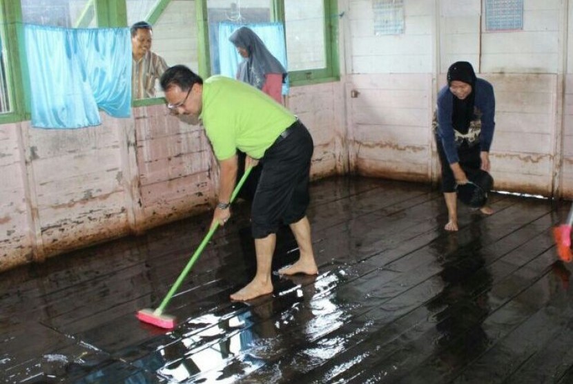 Bupati Banjar Sultan H Khairul Saleh membersihkan lantai ruangan kelas SD Tunggul Irang Ulu yang kotor akibat terendam air selama sepekan terakhir.