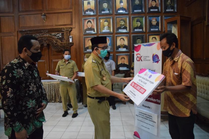 Bupati Banyumas Achmad Husein menyerahkan bantuan dana bantuan RTLH yang berasal dari sumbangan pegawai OJK Purwokerto, Senin (16/11). Penyerahan bantuan disaksikan Kepala OJK Purwokerto, Sumarlan.