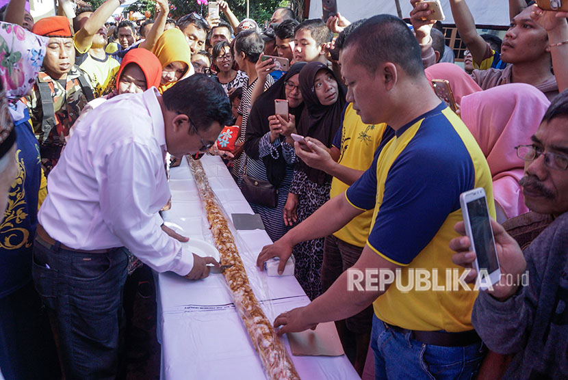 Bupati Pekalongan Asp Kholbihi (kiri) memotong getuk lindri pada perayaan syawalan di Kedungwuni, Kabupaten Pekalongan, Jawa Tengah, Sabtu (23/6).