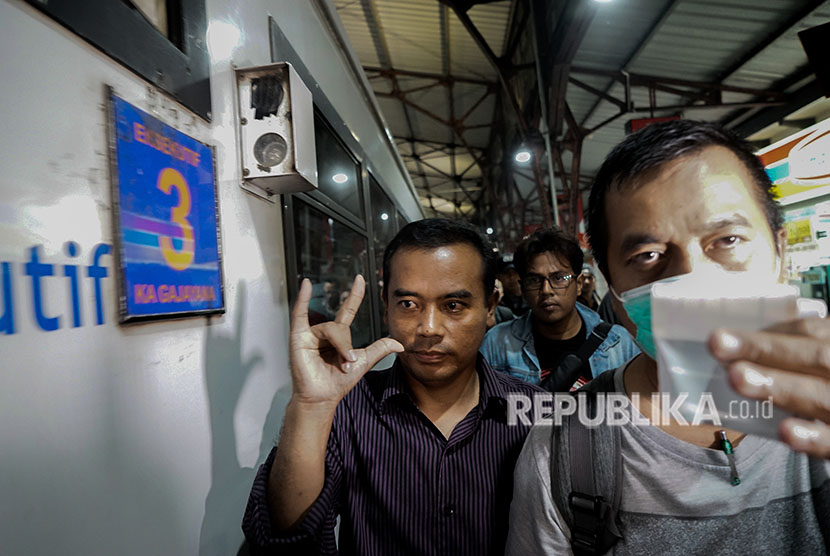 Bupati Purbalingga Tasdi (tengah), membuat tanda jari 'metal' saat akan dibawa ke Jakarta oleh petugas KPK, di Stasiun Purwokerto, Banyumas, Jawa Tengah, Senin (4/6). 
