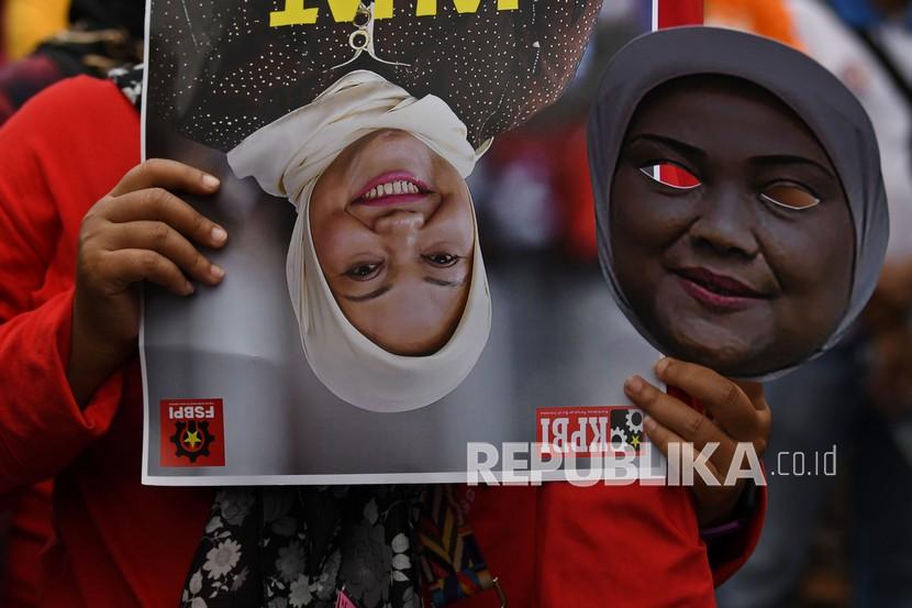 Buruh membawa poster dan topeng Menteri Tenaga Kerja Ida Fauziah saat berunjuk rasa di depan Kantor Kementerian Ketenagakerjaan (Kemnaker), Jakarta, Rabu (16/2/2022). Pada Senin (21/2/2022), Presiden Jokowi meminta menaker merevisi Permenaker JHT.