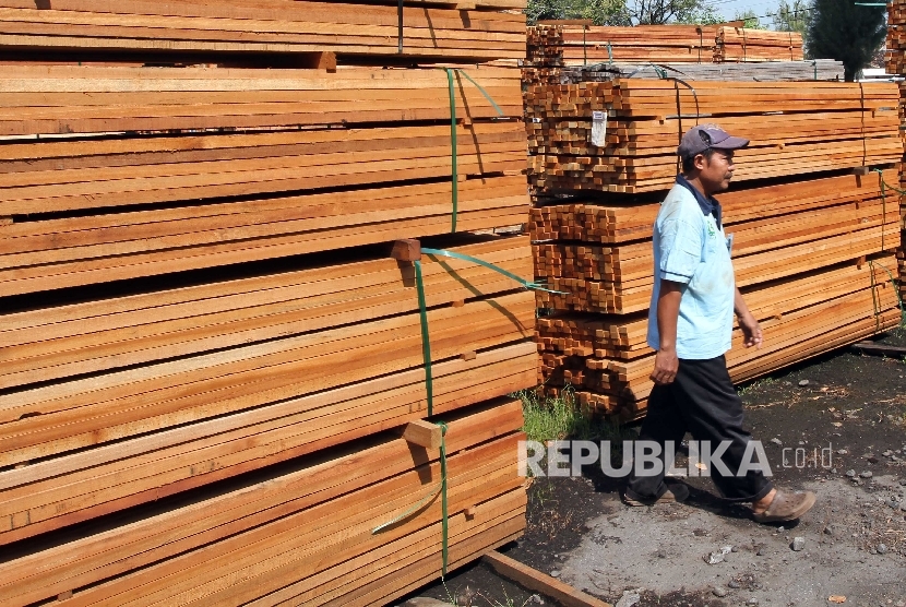  Buruh mengecek tumpukan bahan pengolahan kayu di Jakarta.