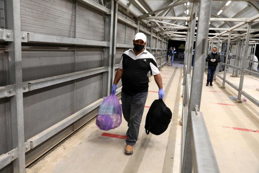 Buruh Palestina dari kota Hebron Tepi Barat membawa barang-barang  melintasi pos pemeriksaan Mitar saat melakukan perjalanan untuk bekerja menuju Israel di tengah pandemi virus corona. Sepekan setelah tiba di bandara, bantuan medis UEA untuk Palestina masih ditolak. Ilustrasi. 