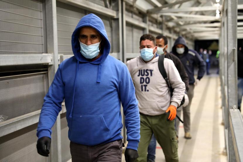 Buruh Palestina dari kota Hebron Tepi Barat membawa barang-barang  melintasi pos pemeriksaan Mitar saat melakukan perjalanan untuk bekerja menuju Israel di tengah pandemi virus coronavirus COVID-19, Selasa (5/5). 