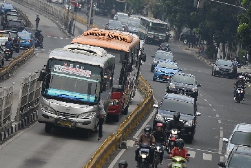Bus Kopaja masuk jalur busway dengan menaikan penumpang sembarangan di Kawasan Duren Tiga, Jakarta Selatan, Selasa (7/4).