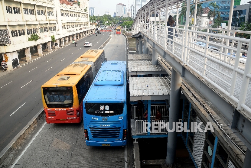 Bus Transjakarta menaikan dan menurunkan penumpang di halte bus Transjakarta. ilustrasi