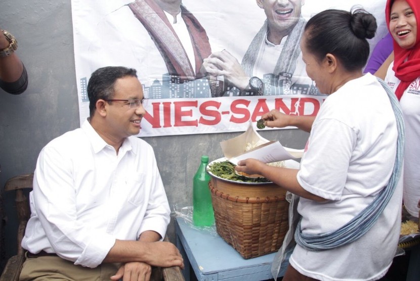 Cagub DKI Jakarta, Anies Baswedan, mencicipi pecel legendaris Sayijatinah (53) atau Bukde Tin saat blusukkan ke Pulogadung, Jakarta Timur, Selasa (10/1). 