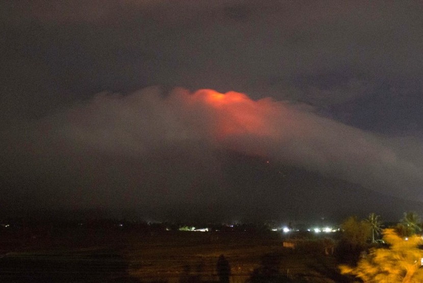 Cahaya oranye terlihat dari kawah Gunung Mayon yang diselimuti awan di Kota Legazpi, Provinsi Albay, Filipina, Ahad (14/1).