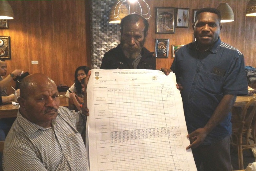 Calon bupati Nabire Decky Kayame (kiri) bersama tim suksesnya membentangkan surat rekapitulasi suara hasil pilkada Nabire, di Jakarta, Ahad (31/1).