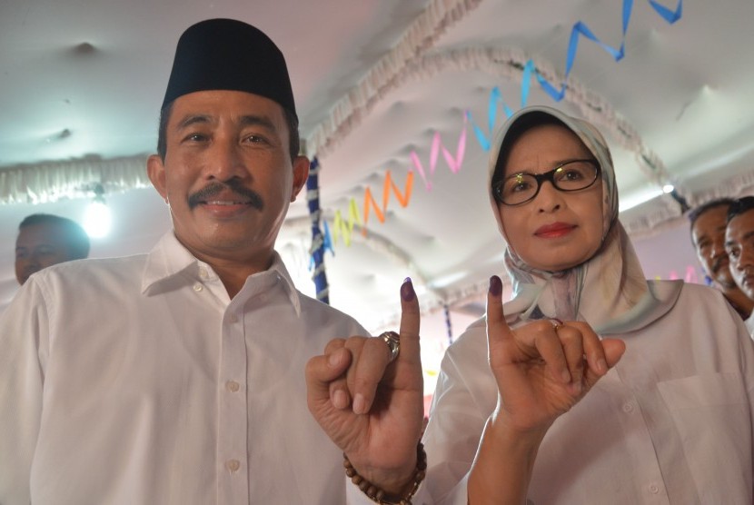 Calon Bupati Tunggal Haryanto (kiri) beserta istri Musus Indarwani menunjukkan jari yang bertinta seusai menggunakan hak suara di Desa Kraci, Batangan, Pati, Jawa Tengah, Rabu (15/2).