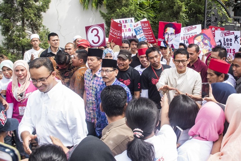 Calon Gubernur DKI Jakarta Anies Baswedan (kiri) dan pasangannya calon Wakil Gubernur Sandiaga S. Uno (kedua kanan) menyapa warga saat kampanye di Cilandak, Jakarta, Senin (19/12). 