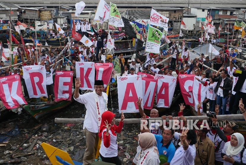 Calon Gubernur DKI Jakarta dengan nomer urut 3 Anies Baswedan (kiri) melambaikan tangan salam tiga jari kepada pendukungnya pada kampanye terakhirnya di kampung nelayan Cilincing Jakarta, Rabu (8/2).
