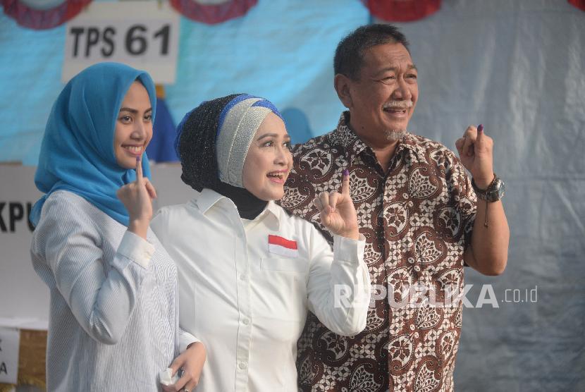 Calon Gubernur Jawa Barat Deddy Mizwar bersama Istri Giselawati Wiranegara bersama keluarga menunjukan tinta di jari usai melakukan pencoblosan di TPS 61, Jatiwaringin, Bekasi, Jawa Barat, Rabu (27/6). 