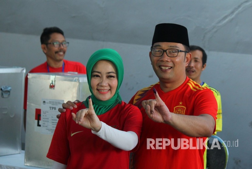 Calon Gubernur Jawa Barat Ridwan Kamil bersama istri Atalia Praratya menunjukan tinta di jari kelingking usai mencoblos dalam Pilkada Serentak 2018, di Tempat Pemungutan Suara (TPS) 21, Cigadung, Kota Bandung, Rabu (27/6).