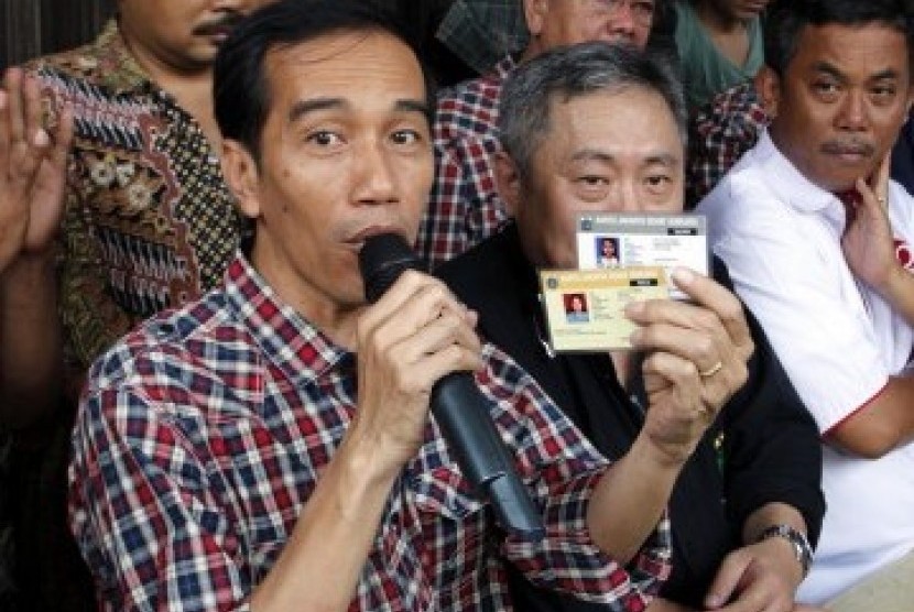 Calon Gubernur Joko Widodo memperlihatkan kartu sehat dan kartu pendidikan, di Jalan Gajah Mada-Hayam Wuruk, Ahad (1/3). (Republika/Adhi Wicaksono)