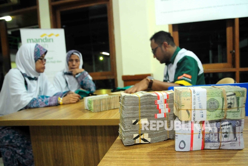 Calon jamaah haji kloter 28 asal Cilegon, Banten membeli uang Riyal di konter resmi penjualan Riyal Bank Syariah Mandiri (BSM) di Asramah Haji Pondok Gede Jakarta Timur, Jumat (26/8).