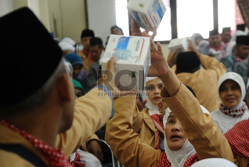  Calon Jamaah Haji kloter 42 Asal Kabupaten Garut, mengambil obat-obatan saat dibagikan sebelum diberangkatkan di asrama haji Bekasi, Jawa Barat, Ahad (6/9).   (Republika/Tahta Aidilla)