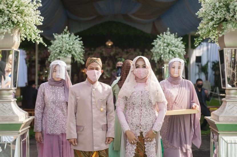 Calon pengantin wanita diiringi keluarga memasuki lokasi akad nikah di masa zona hijau Covid-19 Kota Sukabumi, Ahad (12/7).