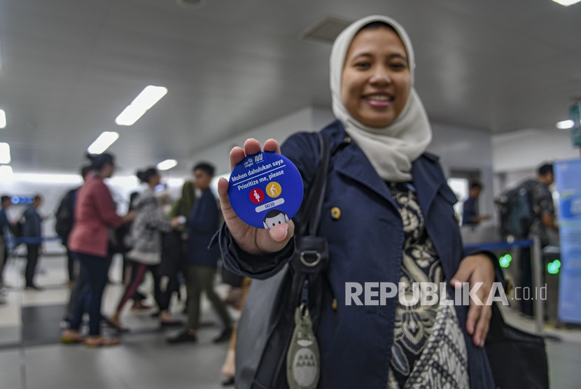 Calon pengguna transportasi Moda Raya Terpadu (MRT) menunjukan pin prioritas di Stasiun MRT Jakarta, Jumat (10/1/2020). 