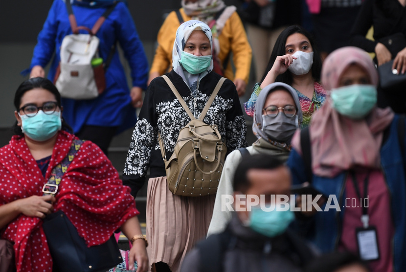 Calon pengguna transportasi umum mengenakan masker saat melintasi kawasan Terowongan Kendal, Jakarta.