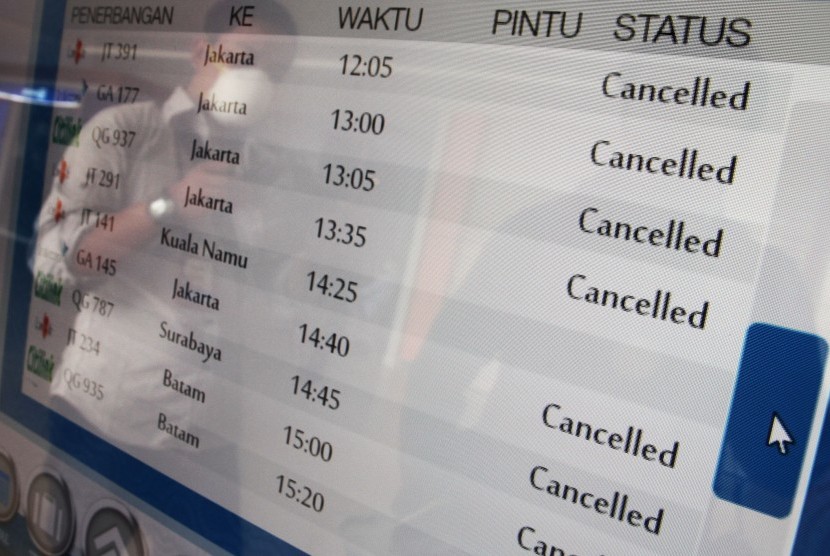 Calon penumpang berada di depan layar informasi jadwal penerbangan yang memperlihatkan sejumlah penerbangan dibatalkan di Bandara Sultan Syarif Kasim II Pekanbaru, di Pekanbaru, Riau, Selasa (6/10). 