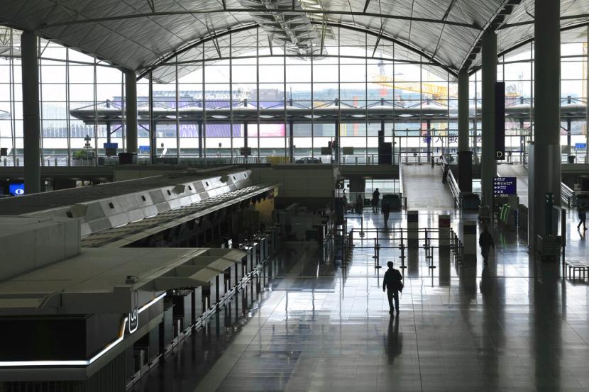 Calon penumpang berjalan di Bandara Hong Kong yang kosong pada Jumat (18/2/2022). Pemimpin Hong Kong Carrie Lam mengatakan akan membuka kembali penerbangan dan mengurangi durasi karantina penumpang luar negeri.