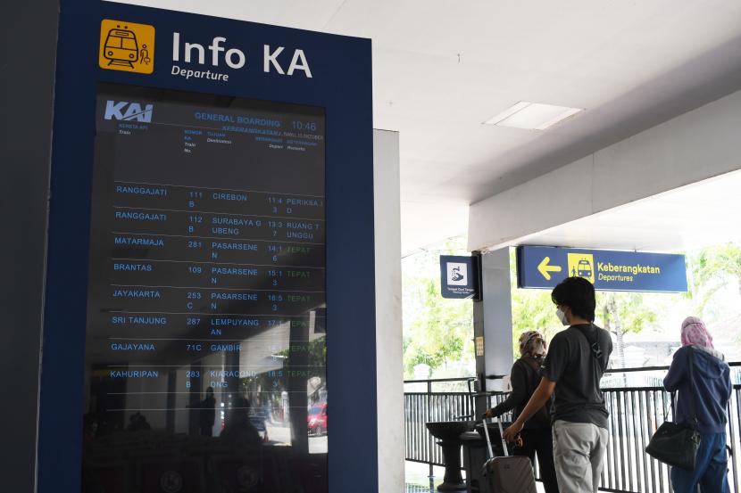 Calon penumpang melintas di dekat papan informasi di Stasiun Kereta Api (KA) Madiun, Jawa Timur. 