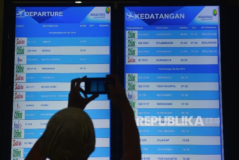  Calon penumpang memotret jadwal keberangkatan dan kedatangan pesawat di Bandara Halim Perdanakusuma, Jakarta, Senin (4/4) malam.  (Republika/Raisan Al Farisi)