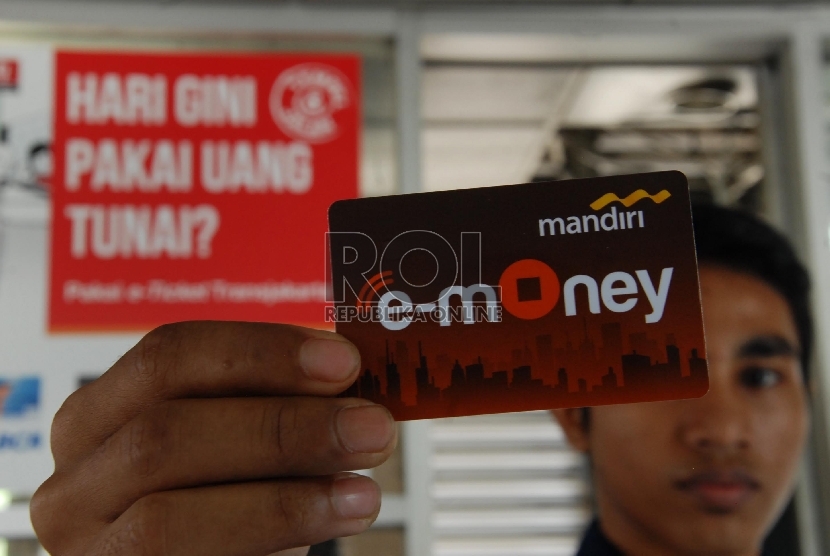  Calon penumpang menunjukkan kartu E-Money di halte Harmoni, Jakarta Pusat.