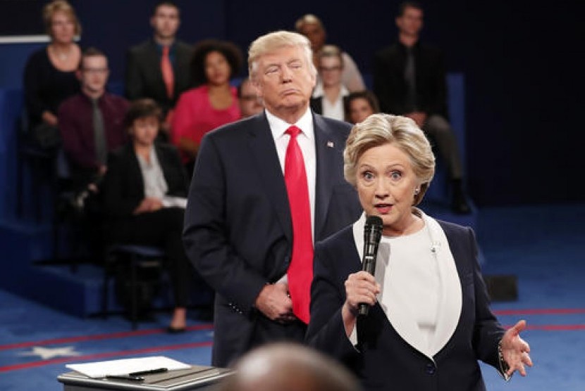 Calon presiden AS Donald Trump berdiri di belakang rivalnya Hillary Clinton saat debat kedua di Washington University, St Louis, Ahad, 9 Oktober 2016.