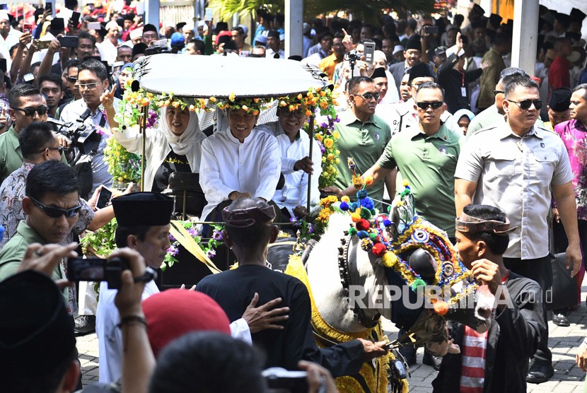 Calon Presiden nomor urut 01 Joko Widodo (tengah) didampingi putri almarhum KH Abdurrahman Wahid, Yenny Wahid (kiri) menaiki delman menuju lokasi Deklarasi Akbar Ulama se-Madura untuk Jokowi-Maruf di Bangkalan, Madura, Jawa Timur, Rabu (19/12/2018). 