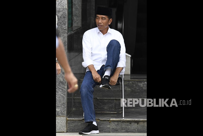 Calon Presiden petahana Joko Widodo (kiri) mengenakan sepatu usai menunaikan salat di Masjid Al Markaz Al Islami, Makasar, Sulawesi Selatan, Minggu (31/3/2019). 