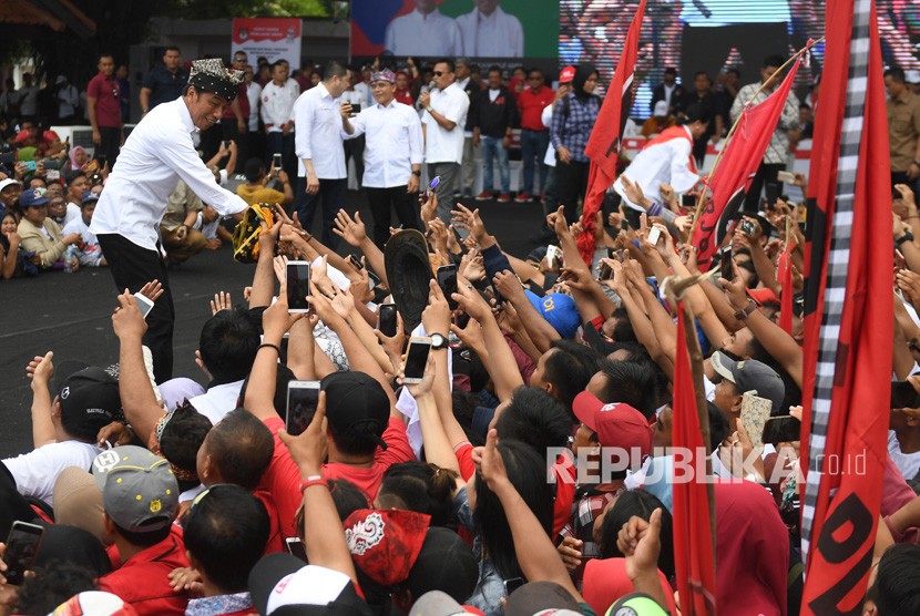 Calon Presiden petahana nomor urut 01 Joko Widodo (kiri) berjabat tangan dengan pendukung saat kampanye terbuka di Banyuwangi, Jawa Timur, Senin (25/3/2019). 