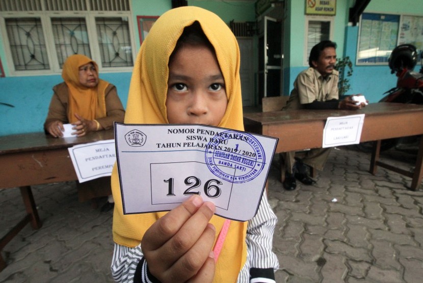 Calon siswa menunjukkan nomor pendaftaran siswa baru di Sekolah Dasar Negeri 1(SDN) Lhokseumawe, Aceh, Senin (20/5/2019).