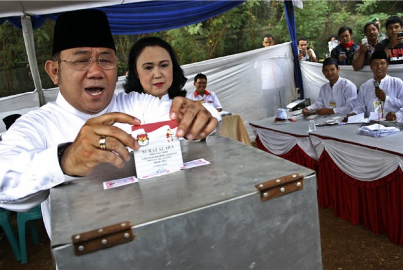 Calon Wakil Gubernur DKI Jakarta, Nachrowi Ramli atau Nara (kiri), bersama isteri Alfina Evi Maria (kedua kiri) memberikan hak suaranya di TPS 029 Kelurahan Batu Ampar, Kramat Jati, Jakarta Timur, Kamis (20/9). 