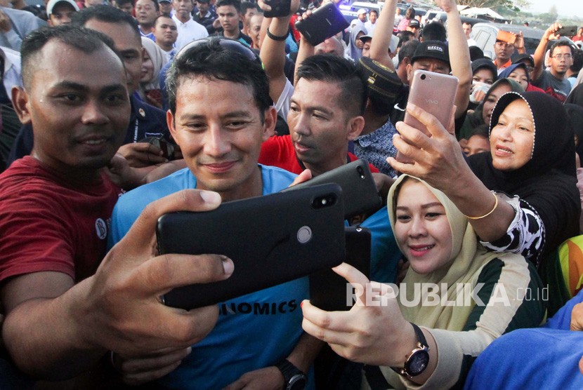 Calon Wakil Presiden nomor urut 02 Sandiaga Salahudin Uno (kedua kiri) melayani permintaan swafoto dari pendukungnya usai lari pagi mengelilingi waduk Lhokseumawe di Aceh, Ahad (3/2/2019).