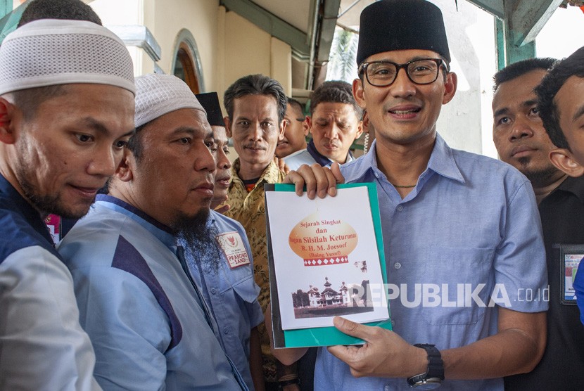 Calon Wakil Presiden nomor urut 02 Sandiaga Uno (kedua kanan) menunjukan buku sejarah Syech Baing Yusuf usai berziarah ke makam R. H.M. Joesof atau yang dikenal dengan Syech Baing Yusuf saat berkampanye di Purwakarta, Jawa Barat, Rabu (14/11/2018).