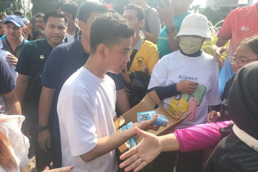 Calon Wakil Presiden RI Gibran Rakabuming Raka membagikan susu kepada warga yang sedang berolahraga di Bundaran HI, Jakarta Pusat, Ahad (3/12/2023).