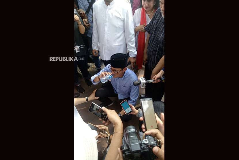 Calon wakil presiden Sandiaga Uno mengambil minum usai berhasil keluar dari kerumunan massa pendukungnya di depan gerbang Komisi Pemilihan Umum (KPU) di Jalan Imam Bonjol, Jakarta Pusat, Jumat (10/8). 