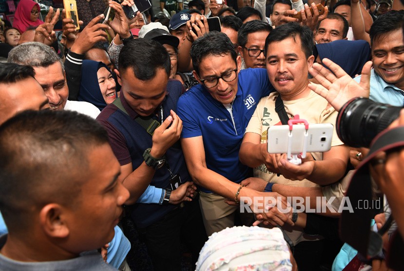 Calon Wakil Presiden Sandiaga Uno (tengah) menyapa pengunjung dan pedagang ketika berkunjung ke Pusat Grosir Surabaya (PGS), Surabaya, Jawa TImur, Ahad (21/10/2018). 