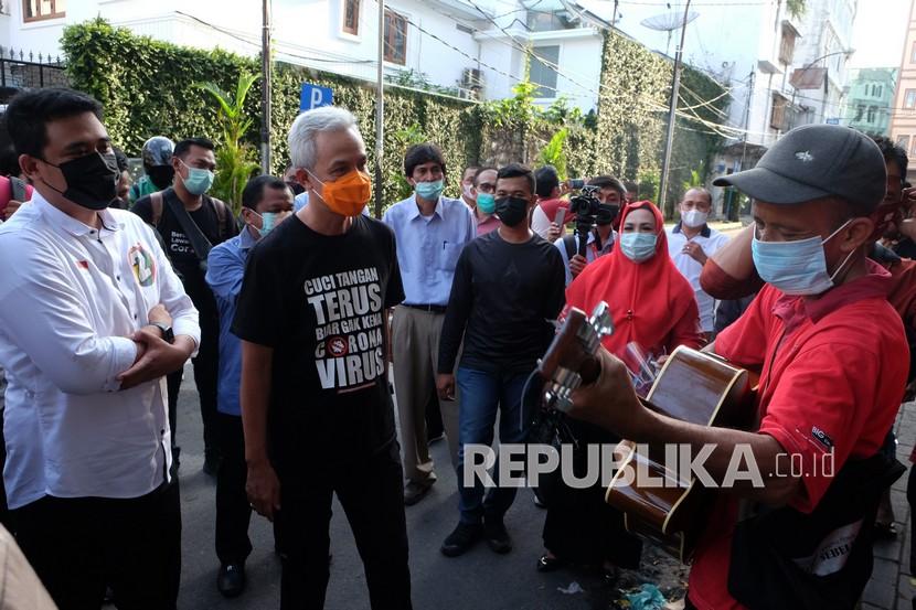 Wali Kota Medan nomor urut dua Bobby Nasution (kiri) mendengarkan lagu yang dinyanyikan pengamen saat mengunjungi kawasan kota tua Kesawan, di Medan, Sumatera Utara.