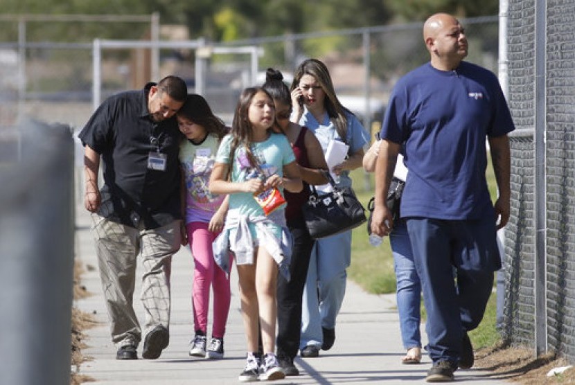 Camilo Rocha (kiri) menenangkan putrinya, Serina (11 tahun) yang merupakan siswa North Park Elementary School setelah bertemu di Cajon High School, Senin (10/4) di San Bernardino, Kalifornia usai penembakan.