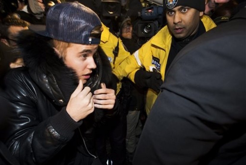 Canadian musician Justin Bieber is swarmed by media and police officers as he turns himself in to city police for an expected assault charge, in Toronto, on Wednesday, Jan. 29, 2014. 