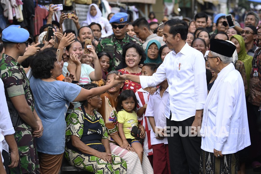 Capres petahana Joko Widodo (kedua kanan) dan cawapres Ma'ruf Amin (kanan) menyapa warga usai menyampaikan pidato kemenangannya sebagai Presiden Republik Indonesia periode 2019-2024 di Kampung Deret, Tanah Tinggi, Johar Baru, Jakarta Pusat, Selasa (21/5/2019).