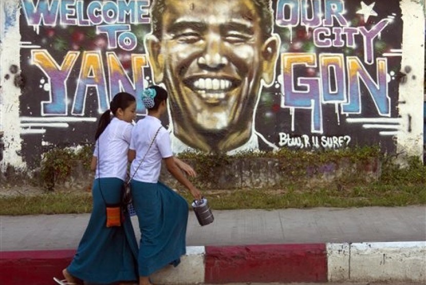 Myanmar university students walk past a graffiti of US President Barack Obama on a roadside in Yangon, Myanmar Friday, Nov. 14, 2014.